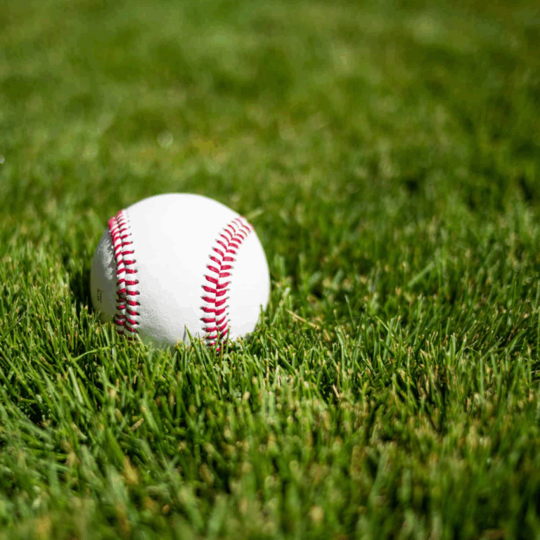 Una pelota de béisbol blanca con costuras rojas descansando sobre la exuberante hierba verde Zeon Zoysia.