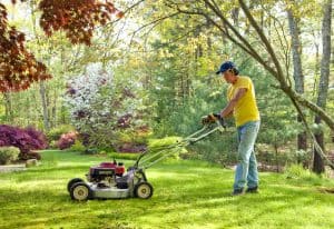 caucasian man in a hat mowing the lawn